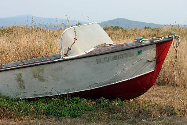 Old and Weathered Red and White Fishing Boat Abandoned in a Field