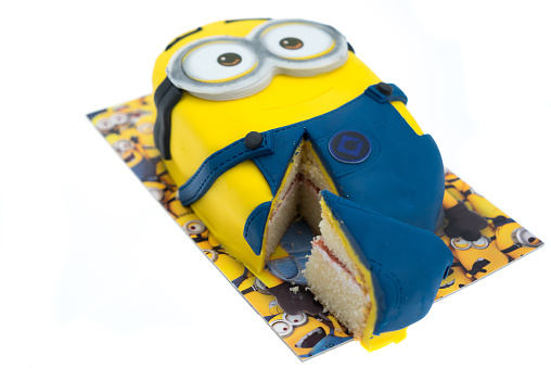 Folkestone, United Kingdom - October 27, 2015: Minions character party cake isolated on white background. Minions are action figures from the movie Despicable Me 2 animated film produced by Illumination Entertainment for Universal Pictures.