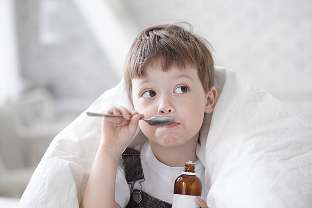 ragazzo bere sciroppo per la tosse - brown boy foto e immagini stock