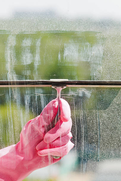 istock hand in pink glove cleans window pane by squeegee 495006629
