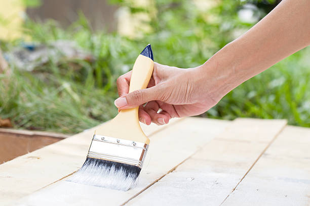 istock hand worker holding brush painting white on wood texture 495017122