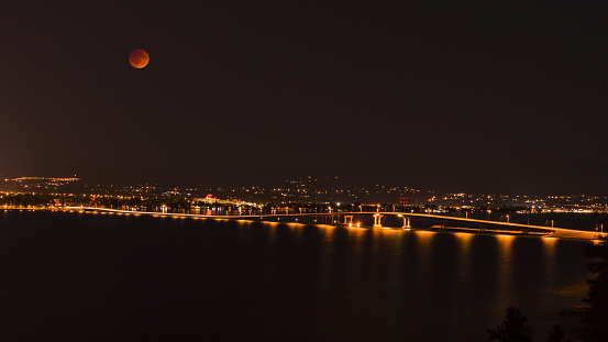 A view of the bridge over Okanagan Lake between West Kelowna and Kelowna Brititsh Columbia Canada at night with a full moon during the lunar eclipse. September 27 2015