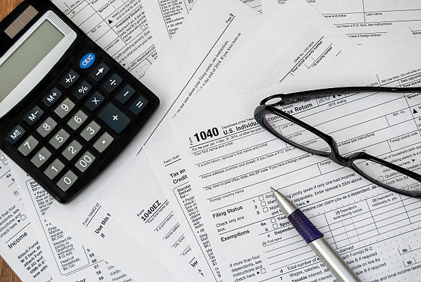 pen, glasses and calculator on the tax form stock photo