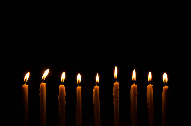 istock nine light candles burning brightly in the black background 495034444
