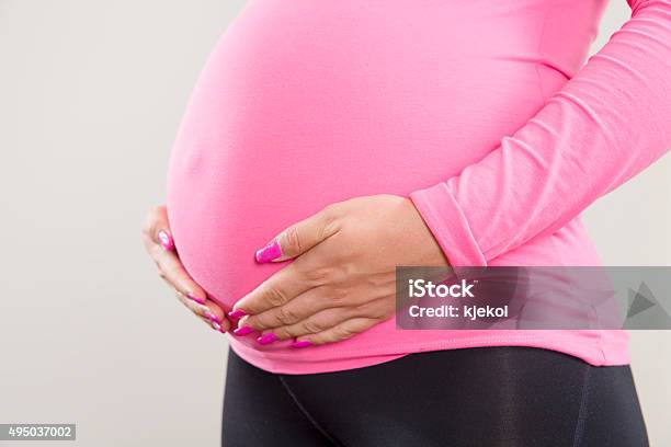 Pregnant Woman Holds On Her Swollen Belly Stock Photo - Download Image Now - 2015, Abdomen, Adult