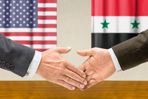 Representatives of the USA and Syria shake hands