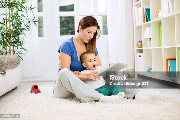 Happy Smiling Mother And Child Playing On Tablet Stock Photo - Download Image Now - 2015, Adult, Boys