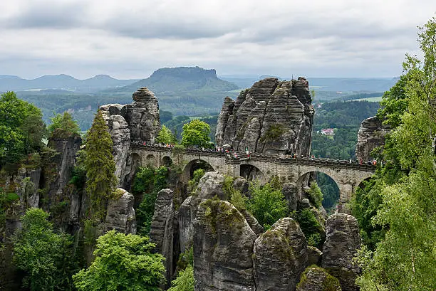 Bastei bridge from lookout point Ferdinandstein at the top of the Wehltürme - in the background the Lilienstein. Saxon Switzerland Germany National park Elbe Sandstone Mountains Bastei. Tourists are visiting the mountain landscape bridge