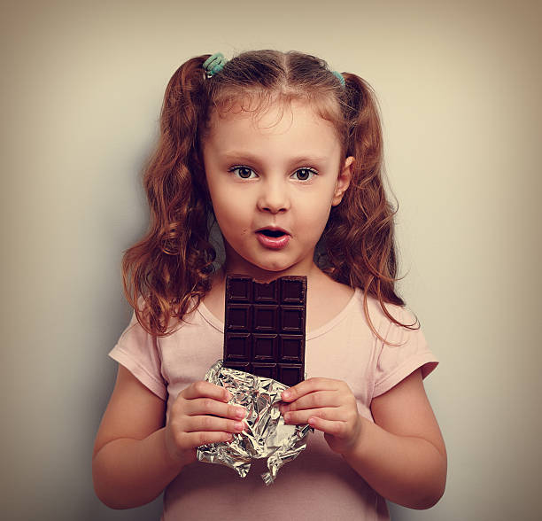istock Fun expression kid girl eating dark chocolate and looking happy. 495048812