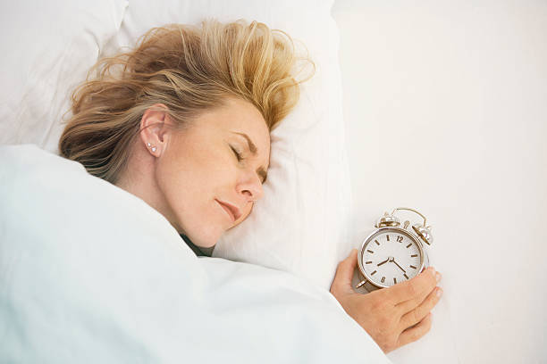 istock woman sleeping with alarm clock 495048828
