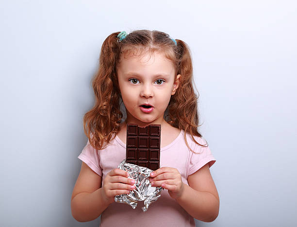 istock Fun expression kid girl eating dark chocolate and looking happy. 495052048