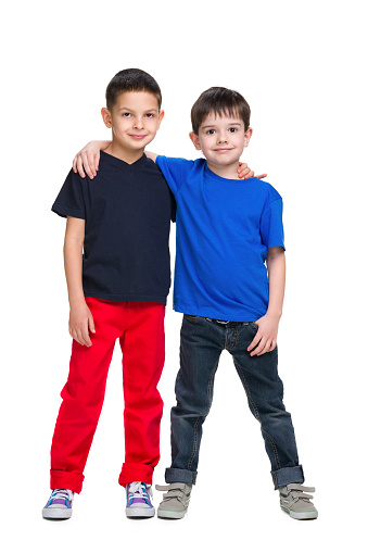 Two happy young boys stand together against the white background