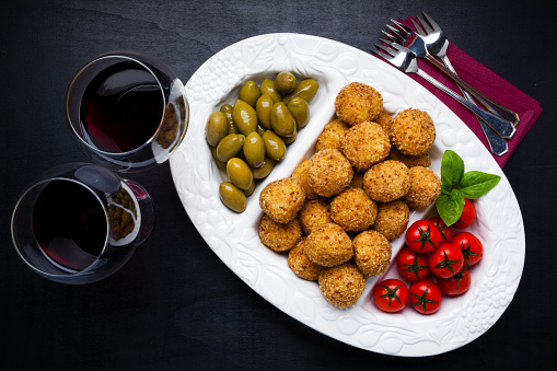 Healthy Italian Appetizer with Risotto Balls Arancini , green Olives , tomato and red Wine Sicilian homemade Snack