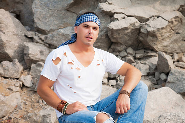 Beautiful attractive man sitting on a rock in the mountains