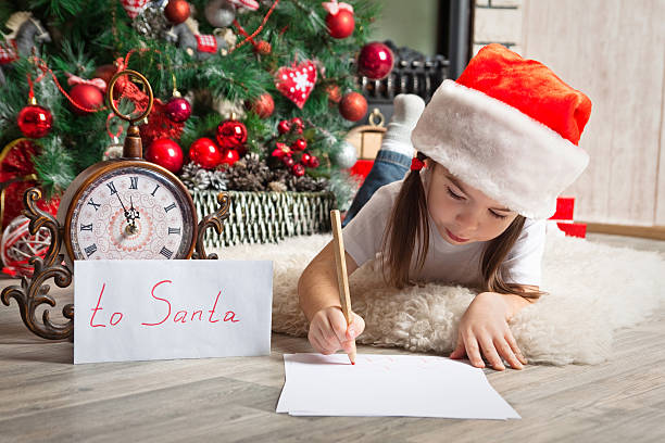 linda menina com chapéu de papai noel escreve carta de papai - clock baby christmas small - fotografias e filmes do acervo