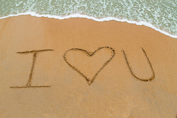istock I Love You drawn on sandy beach with wave approaching 495080616