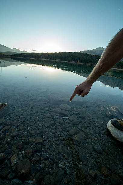 istock Finger touches surface of mountain lake. sunset 495082202