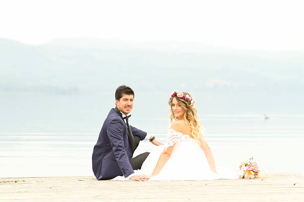 istock Bride and groom posing at a dock on the lake 495098206