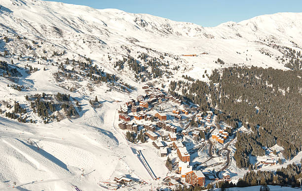 Panoramic view down a mountain valley Panoramic view of a snow covered mountain range looking down valley with village ski resort courchevel stock pictures, royalty-free photos & images