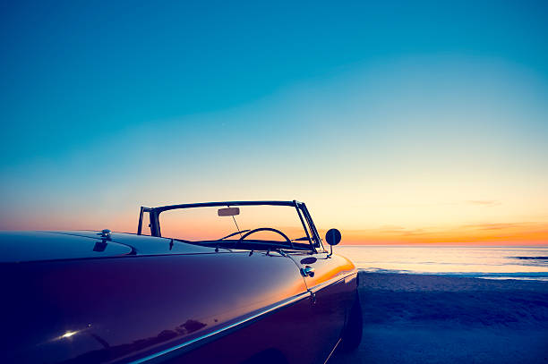 umwandelbares am strand bei sonnenuntergang oder sonnenaufgang. - road trip collectors car sports car convertible stock-fotos und bilder