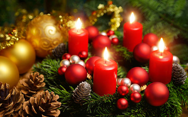 Advent wreath with 4 burning candles Studio shot of a nice advent wreath with baubles and four burning red candles christmas ornament christmas decoration red religious celebration stock pictures, royalty-free photos & images