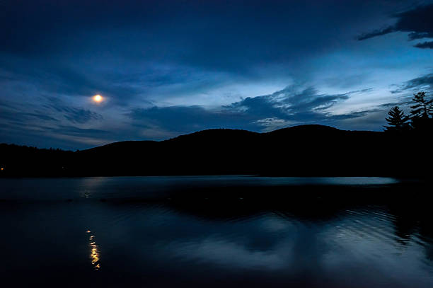 istock Hills and moon reflected on lake at night 495117946