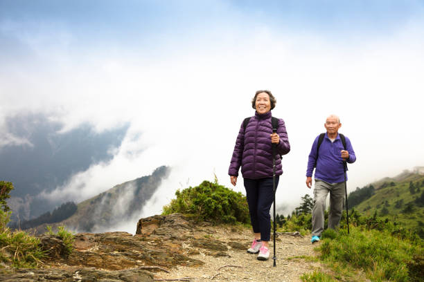 coppia felice asiatico senior escursioni in montagna - hiking senior adult exercising outdoors foto e immagini stock