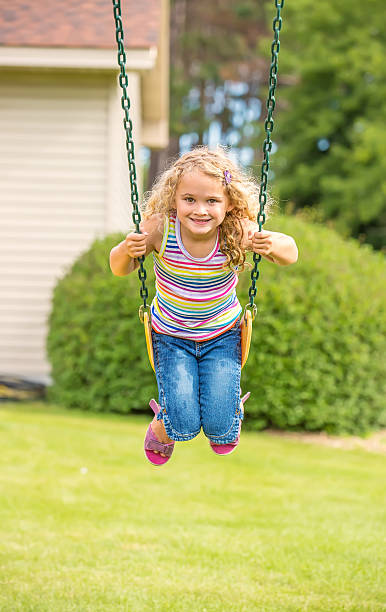 istock Young Girl Swinging in Front Yard 495119672