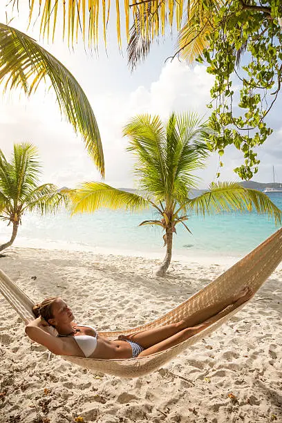 woman in bikini relaxing in a hammock at a tropical beach in Salomon Bay, St.John, US Virgin Islands