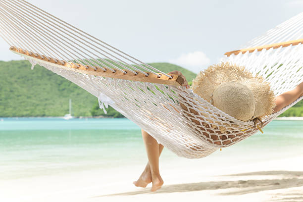 unrecognizable woman in hammock at Maho Bay Beach, St.John, USVI unrecognizable single young woman in summer hat relaxing in a hammock at a tropical Caribbean beach at Maho Bay, St.John, US Virgin Islands saint martin caribbean stock pictures, royalty-free photos & images