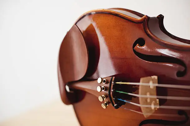Photo of Close up violin on pine wood table.