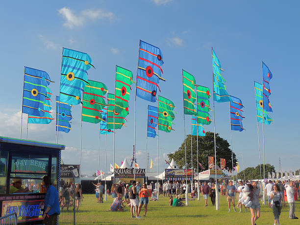 Music Festival Flags Isle of Wight, United Kingdom - June 13th 2014: Festival flags flying and participants arriving early on Friday at the Isle of Wight Music Festival. Spectators mingle around the tents, stalls and fast food outlets in anticipation of the bands starting. 2014 stock pictures, royalty-free photos & images