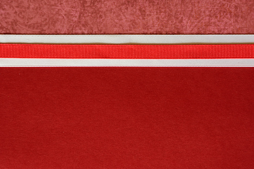 Ribbon border on red colored paper that can be used as a background for christmas scrapbooking, cards, or invitations