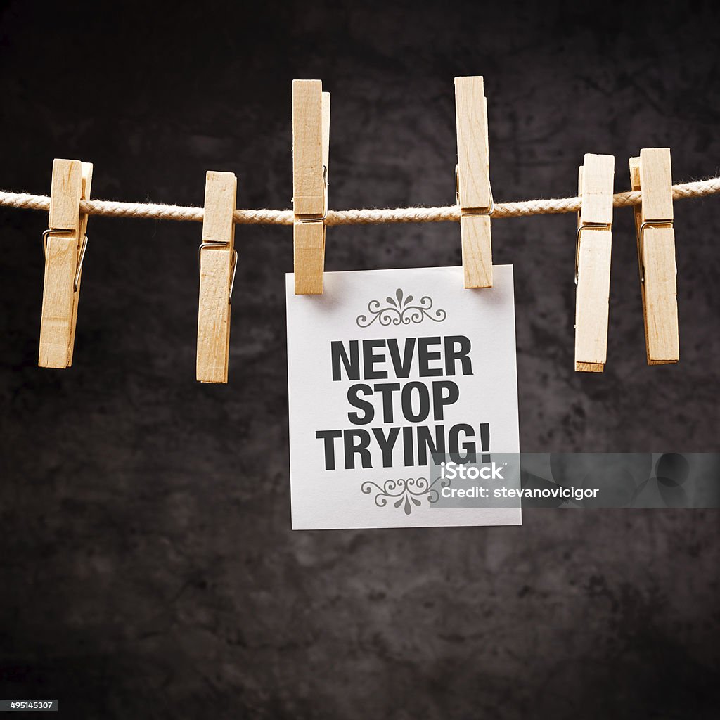 Never Stop Trying Never Stop Trying motivational message printed on note paper and hanged on clothesline with pins. Achievement Stock Photo