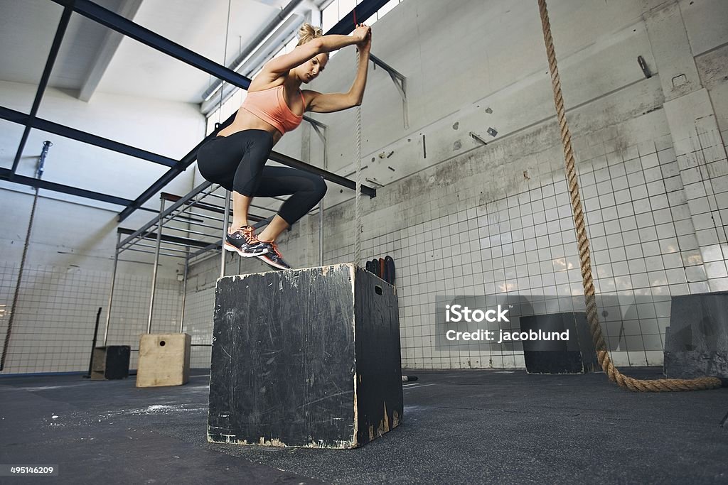 Mujer atleta se realiza caja jumps en el gimnasio - Foto de stock de Entrenamiento combinado libre de derechos