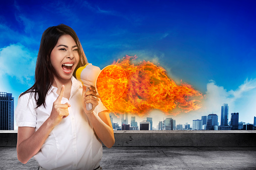 Asian business woman with a megaphone shouting megaphone on fire