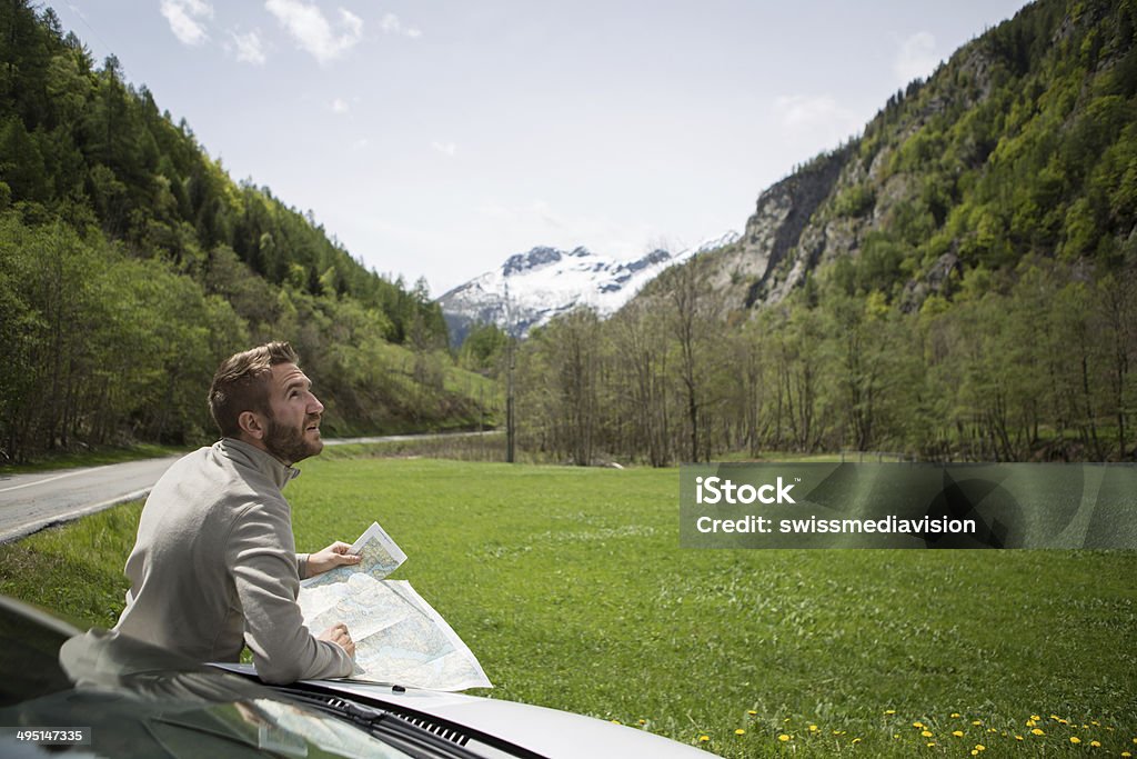 Man consulting directions on map Young man looking for directions on a map, sunny day in Switzerland. Adult Stock Photo