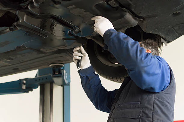 auto mechanic who looks under a car for inspection