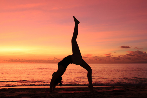 Young woman do yoga at the beach on sunset