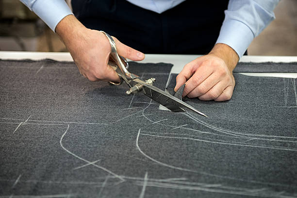 Tailor cutting fabric Tailor cutting fabric using large scissors or shears as he follows the chalk markings of the pattern, close up of his hands tailor photos stock pictures, royalty-free photos & images