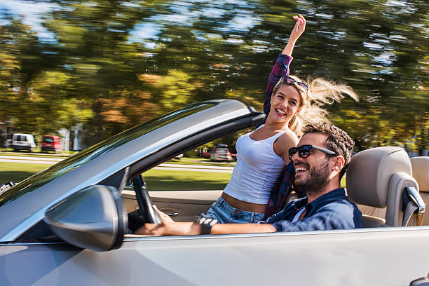 Rear view shot of a mature woman raising her hands in excitement for the roadtrip she is going on with her husband