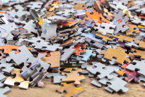 Heap of jigsaw puzzle pieces on a table. Shallow depth of field