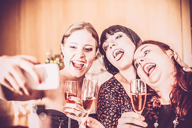 Best Friends Taking Selfie at New Year Party Three cheerful Young women having fun with champagne on a New Year party. Thay taking selfie with iphone. Horizontal color indoors image. rose champagne stock pictures, royalty-free photos & images