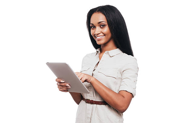 Taking advantages of digital age. Confident young African woman working on digital tablet and smiling while standing against white background isolated businesswoman isolated on white beauty stock pictures, royalty-free photos & images