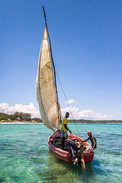 Morondava,Madagascar . 18 october 2023. Malagasy fisherman on homemade wooden old pirogue boat in ocean catches fish with net. selective focus, close-up
