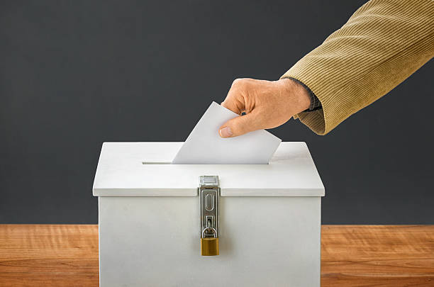 Man putting a ballot into a voting box Man putting a ballot into a voting box nomination stock pictures, royalty-free photos & images