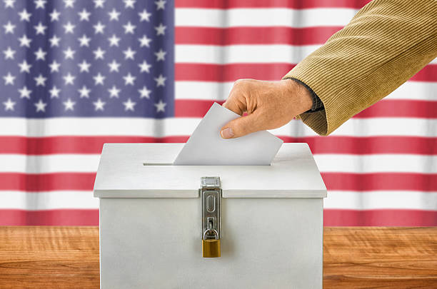 istock Man putting a ballot into a voting box - USA 495190334