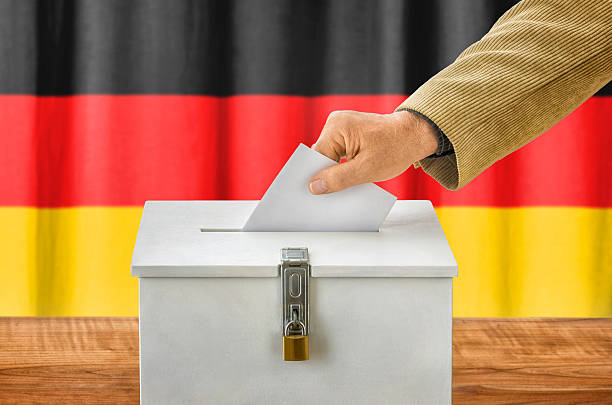 istock Man putting a ballot into a voting box - Germany 495190448