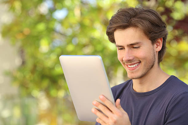 istock Happy man reading a tablet reader outdoors 495191177