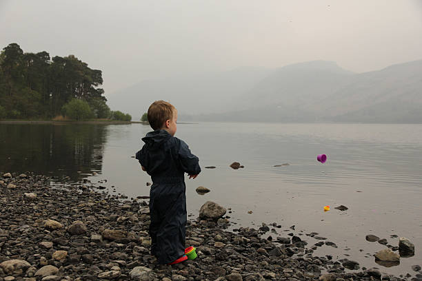 pequeno menino jogando objeto em lake - throwing stone little boys child - fotografias e filmes do acervo